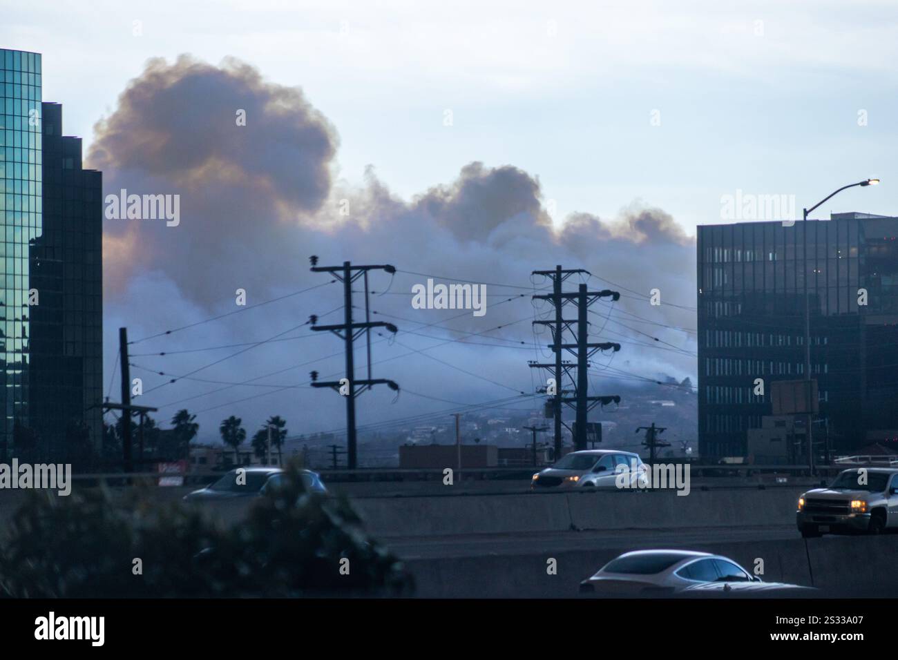 Los Angeles, USA. Januar 2025. Rauchwolken gleiten hinter Stromleitungen über Los Angeles, während Pendler auf dem Highway 405 fahren, während das Feuer der Pacific Palisades in der Nähe von Los Angeles, Kalifornien, brennt. Es wird erwartet, dass starke Winde und trockene Bedingungen das Waldfeuer in den Pacific Palisades verstärken. Quelle: Stu Gray/Alamy Live News. Stockfoto
