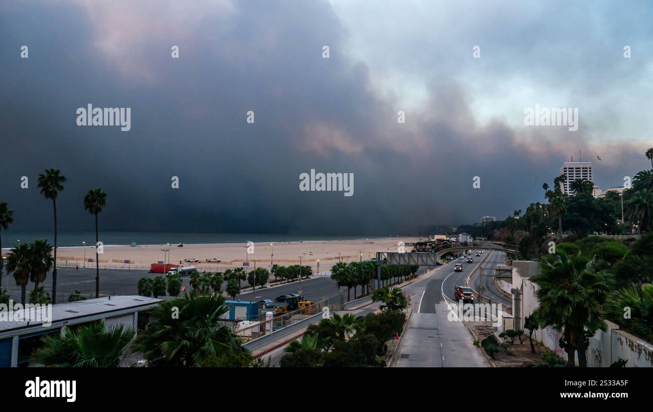 Los Angeles, USA. Januar 2025. Feuerwehrfahrzeuge fahren auf dem ansonsten leeren Pacific Coast Highway (PCH), während Rauchwolken über Santa Monica gleiten, während das Feuer der Pacific Palisades in der Nähe von Los Angeles, Kalifornien, brennt. Es wird erwartet, dass starke Winde und trockene Bedingungen das Waldfeuer in den Pacific Palisades verstärken. Quelle: Stu Gray/Alamy Live News. Stockfoto