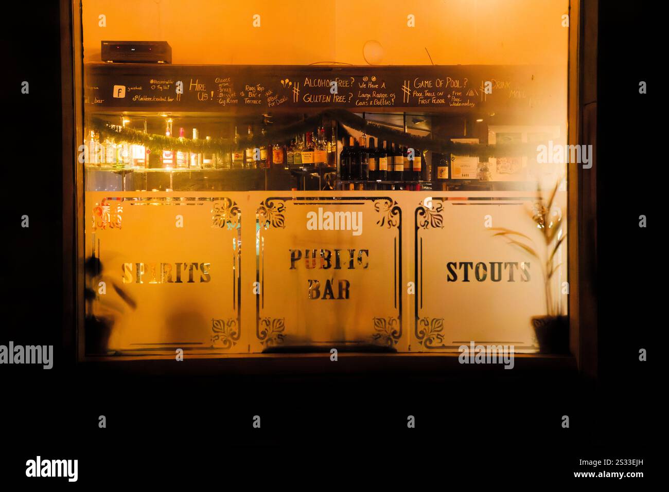 Einladender Blick durch das Fenster des Pubs an einem kalten Abend. Stockfoto