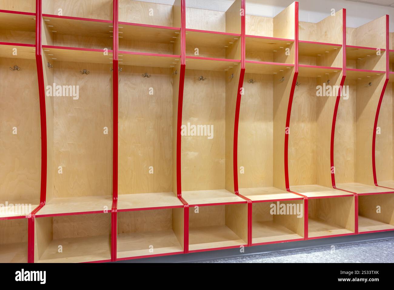 Nahaufnahme eines leeren Schließfachs des Teams, Umkleideraum mit traditionellen offenen Holzschränken mit roter Zierleiste. Stockfoto
