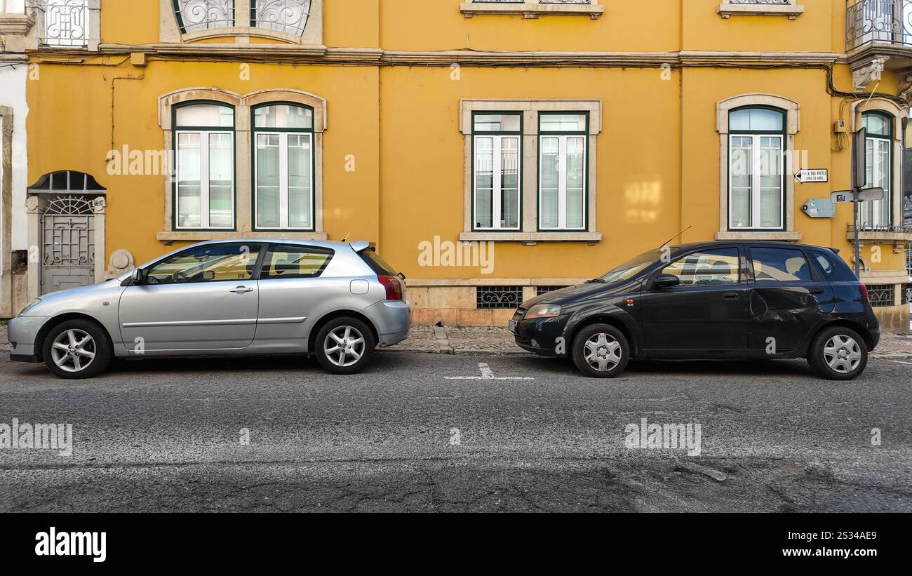 Die Autos parken tagsüber an der Straße in faro, portugal, vor einem alten Gebäude mit einer gelben Außenwand Stockfoto