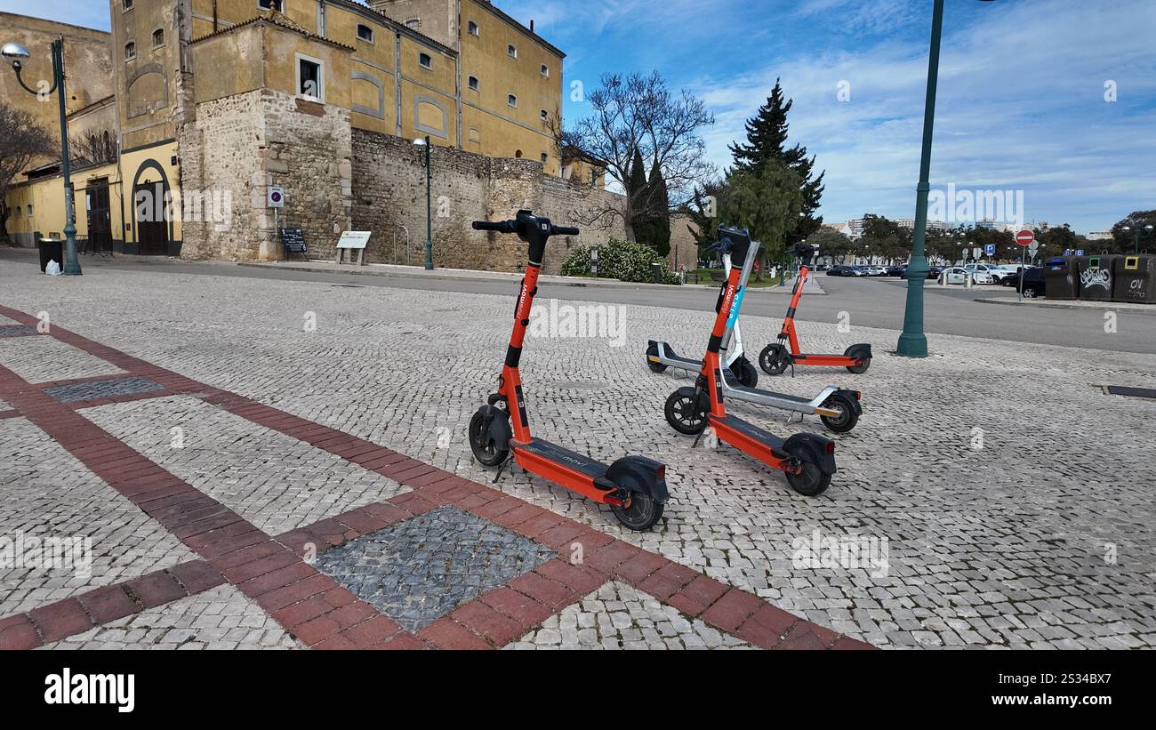 Elektroroller sitzen vor den mittelalterlichen Mauern der Altstadt in Faro, Portugal. Stockfoto