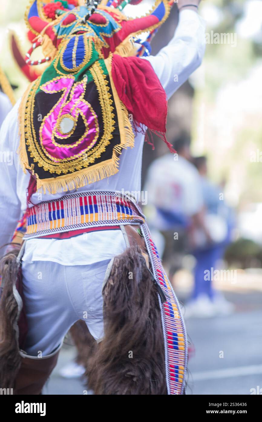 Eine Tänzerin mit bunter Maske und traditioneller Kleidung nimmt an einer lebhaften hispanic Day Parade Teil, die das kulturelle Erbe feiert Stockfoto
