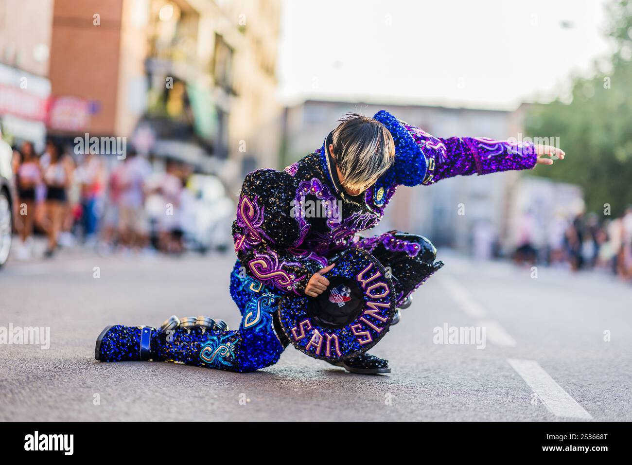 Tänzerin in einem lebendigen, paillettenbesetzten Kostüm, das die Menge mit einer energischen Routine während einer hispanic Day Parade in ihren Bann zieht Stockfoto