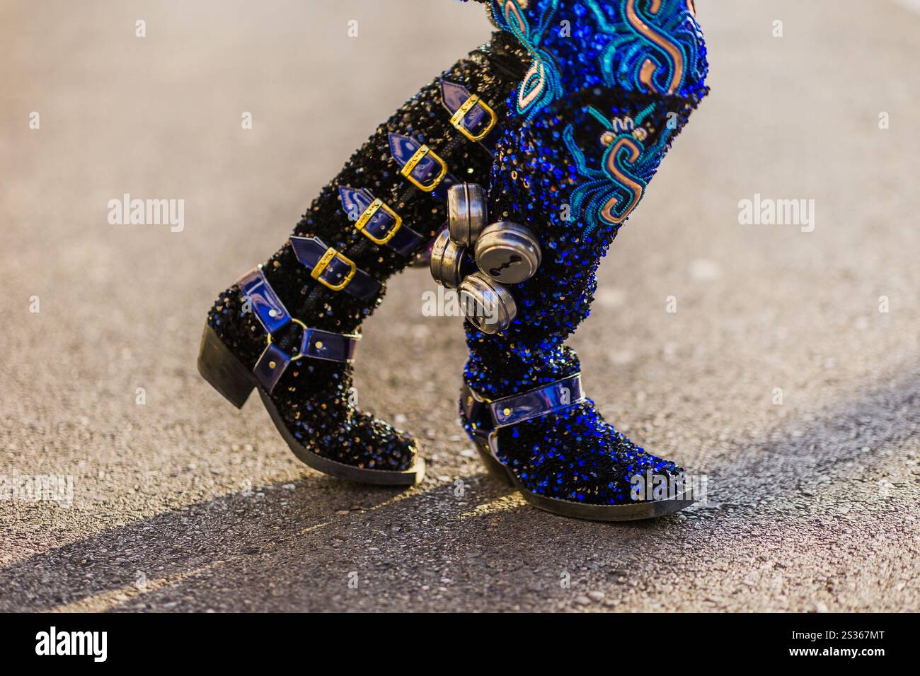 Nahaufnahme der Beine der Tänzerin, die mit kunstvollen Stiefeln und Glocken verziert sind und traditionelle Kleidung während einer lebhaften hispanischen Tagesparade zeigen Stockfoto