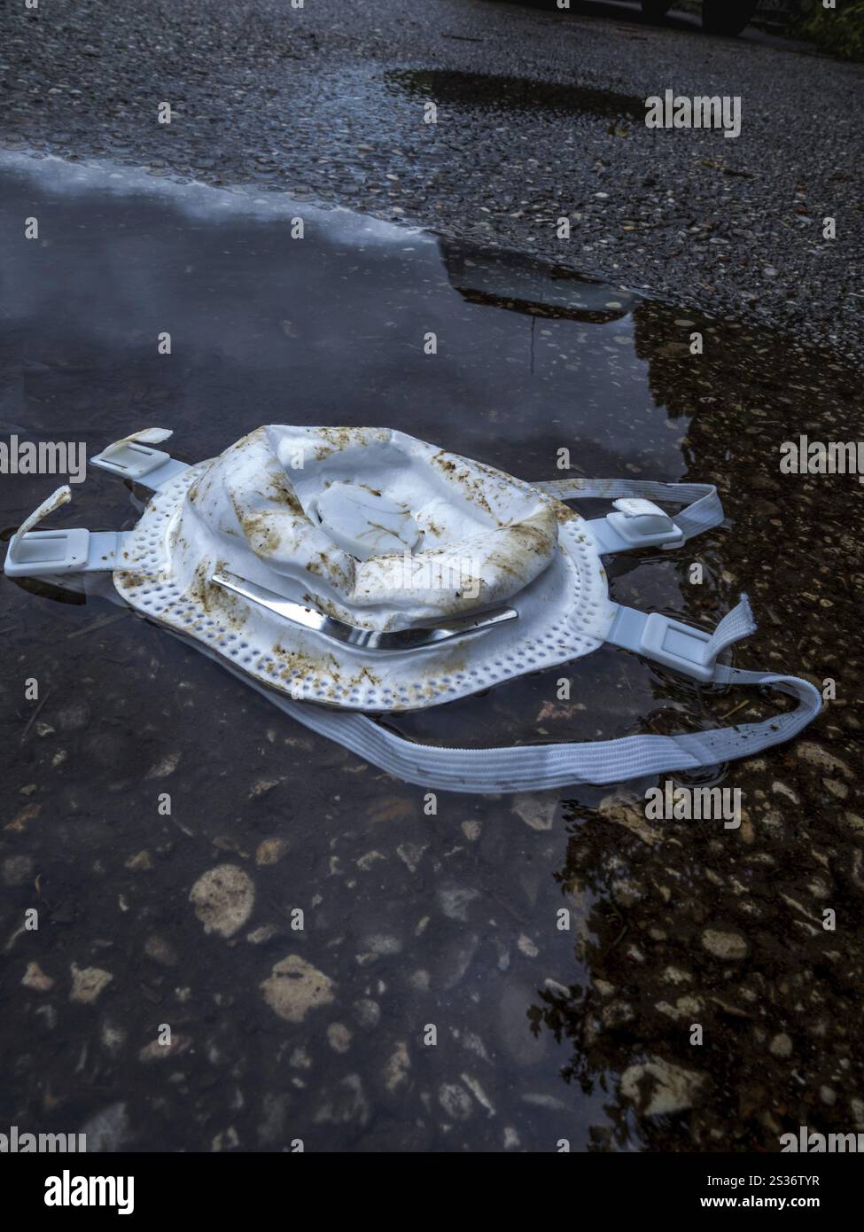 FFP 3 Maske als Schutz gegen Corona liegt in einer Pfütze. Symbolisches Bild für das Ende der Maskenanforderung Stockfoto