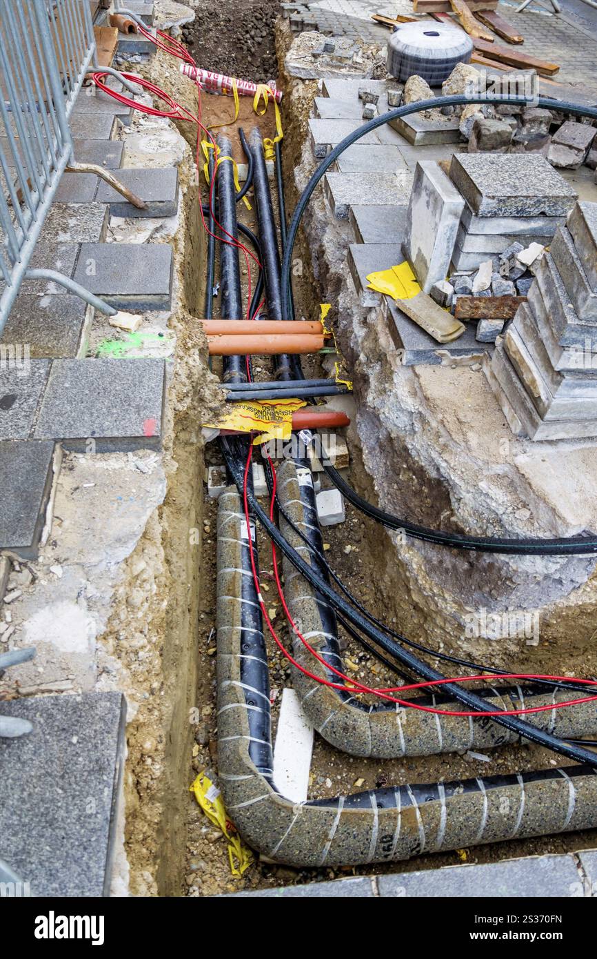 Auf einer Baustelle werden neue Leitungen für Wasser, Heizung, Fernwärme und Strom verlegt. Baugrube mit Versorgungsleitungen Österreich Stockfoto