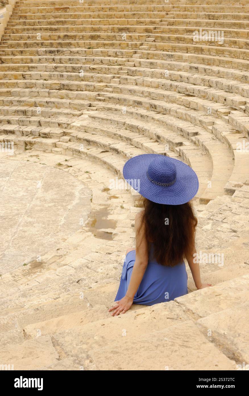 Elegante junge Frau, die allein im alten griechisch-römischen Amphitheater sitzt. Kourion, Zypern. Stockfoto