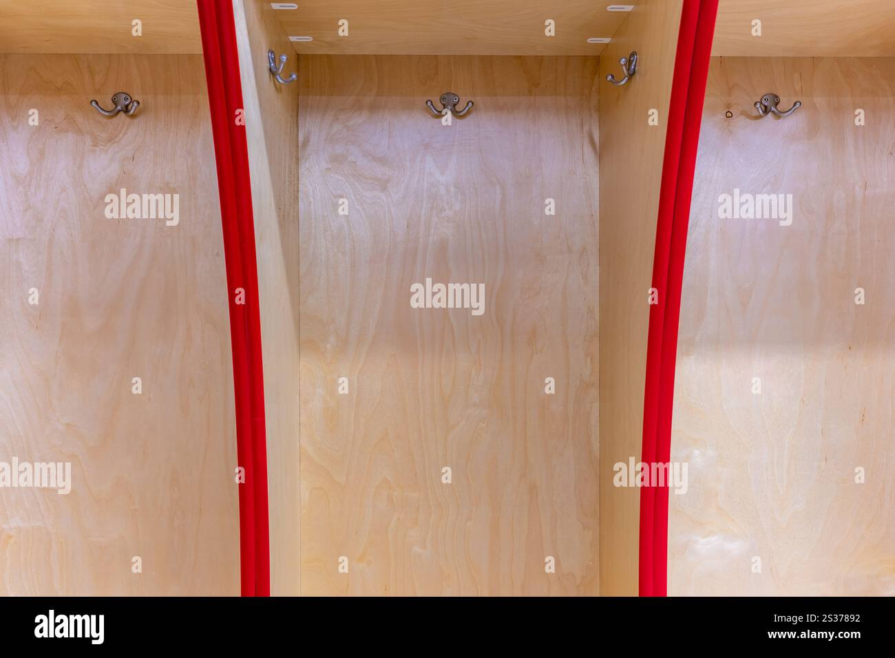 Nahaufnahme eines leeren Schließfachs des Teams, Umkleideraum mit traditionellen offenen Holzschränken mit roter Zierleiste. Stockfoto