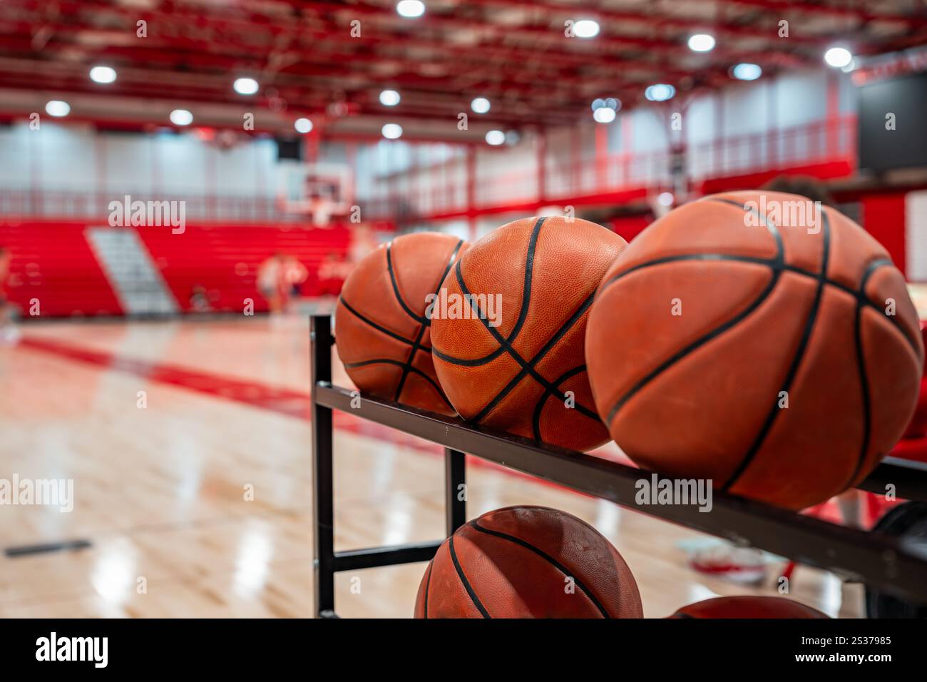 Nahaufnahme von Basketbälle auf einem Lagerregal in einem Fitnessraum mit Holzfußboden und roten Blechfächern. Stockfoto