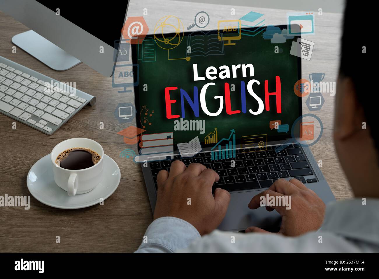 Lernen Sie Englisch auf dem Bildschirm. Der Mann tippt auf einem Laptop, er sitzt an einem Schreibtisch. Das Konzept des Erlernens einer neuen Sprache Stockfoto