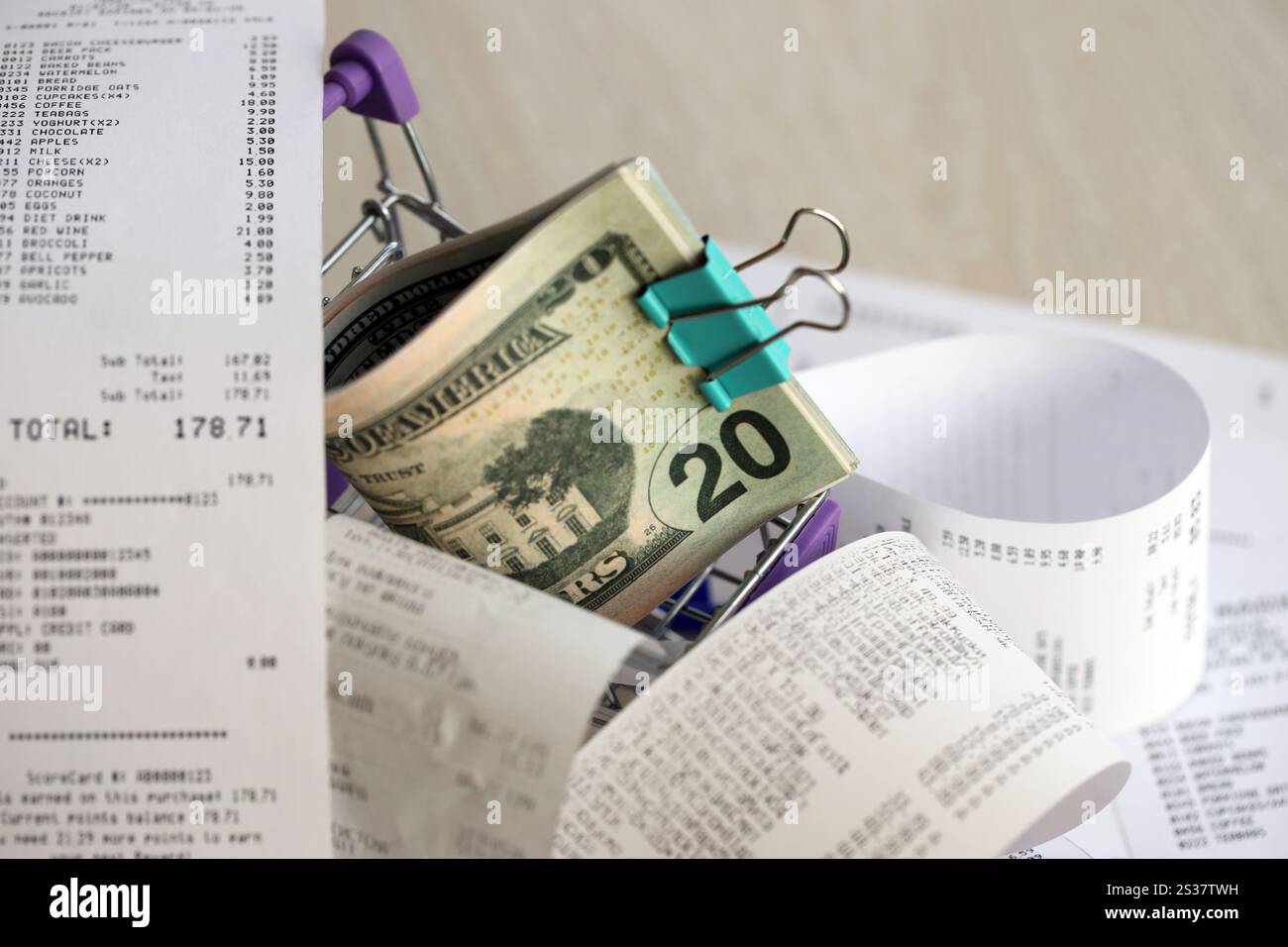 US-Dollar-Haufen im Einkaufswagen, umgeben von vielen Papierquittungen. US-Dollar-Haufen in Einkaufswagen, umgeben von vielen Papieren Stockfoto