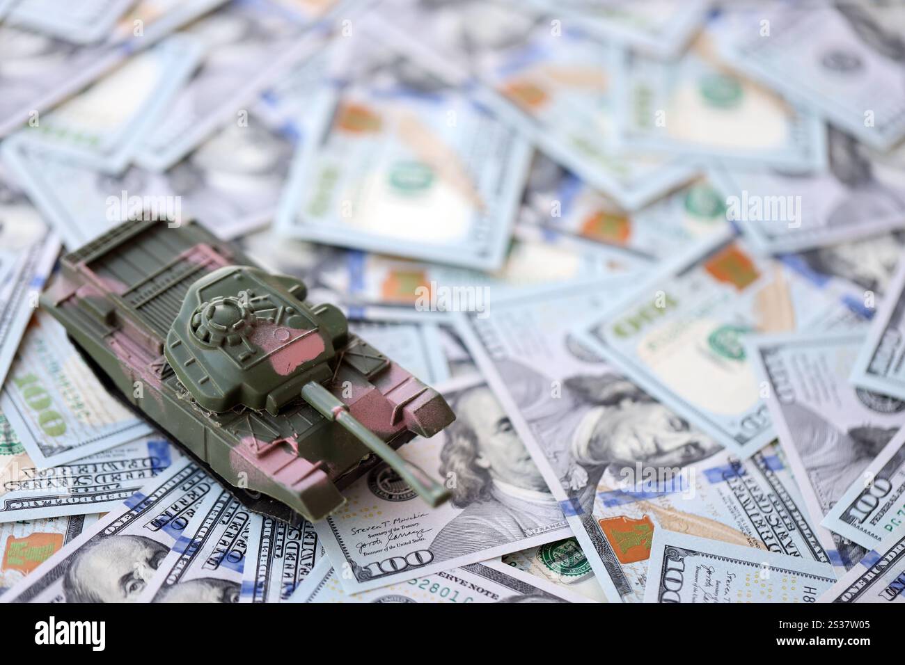 Spielzeugtank auf US-Dollar-Banknoten aus nächster Nähe. Das Konzept der Kriegskosten, der Militärausgaben und der Wirtschaftskrise. Spielzeugtank auf US Hundred Stockfoto