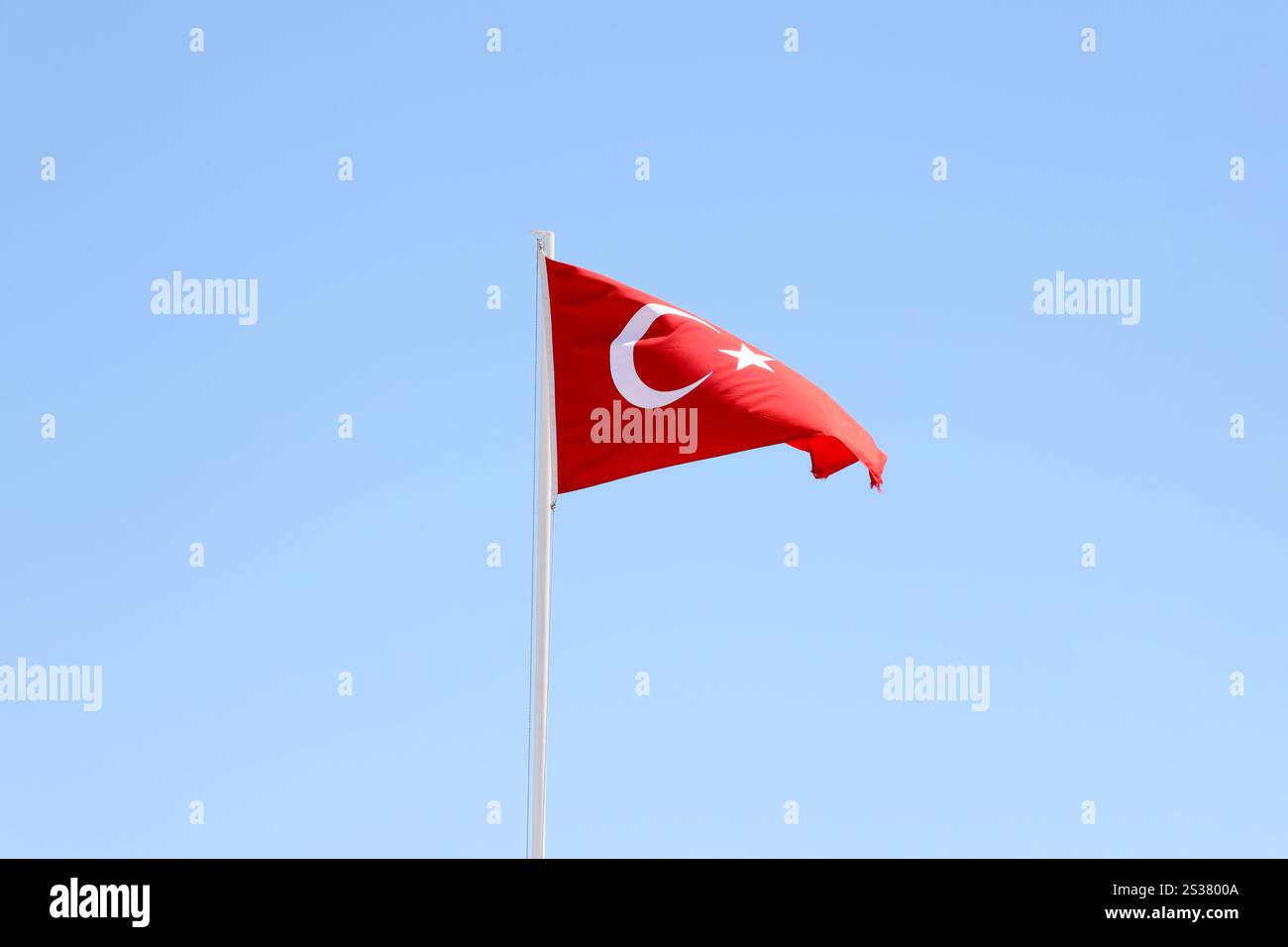 Türkische Flagge auf Fahnenmast winkt im Hintergrund des sauberen blauen Himmels. Weißer Halbmond und Stern auf rotem Hintergrund. Türkische Flagge auf Fahnenmast winkt sauber Stockfoto