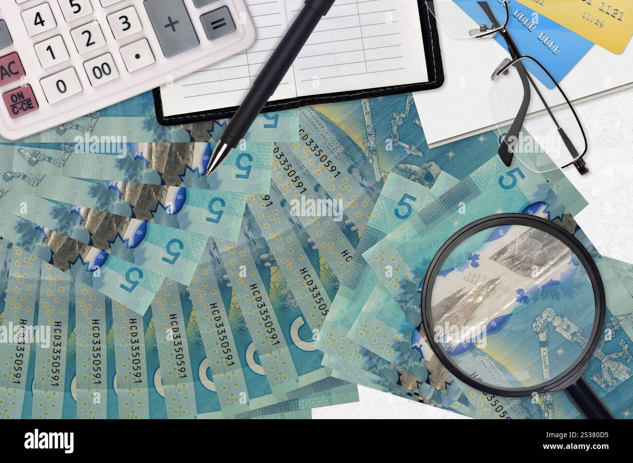5 kanadische Dollarscheine und Taschenrechner mit Brille und Stift. Steuerzahlungssaisonkonzept oder Investitionslösungen. Job mit hohem Gehalt wird gesucht Stockfoto