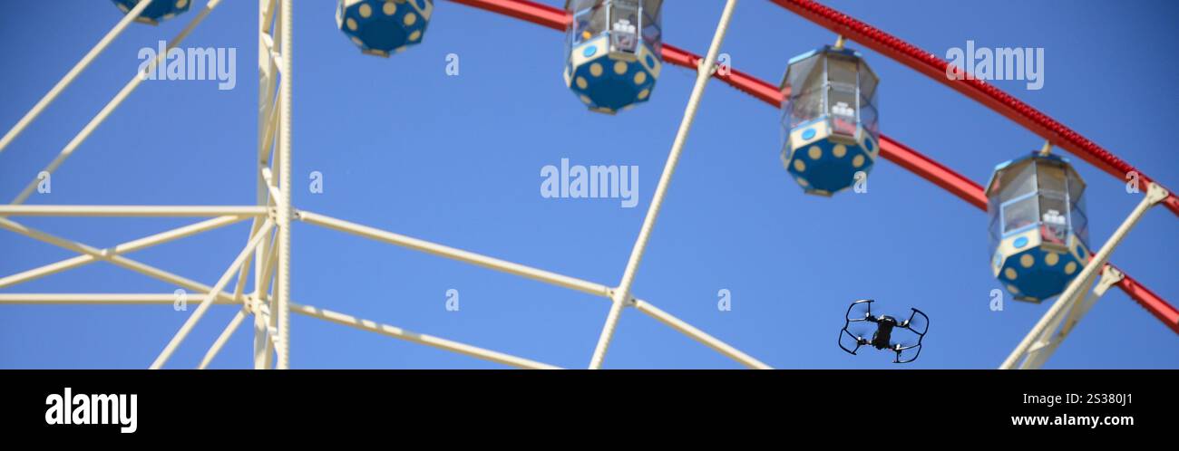 Drohne mit Fotokamera startet vom Land und fliegt für Fotos vor dem Riesenrad. Die Drohne startet vom Land und fliegt, um Fotos zu machen Stockfoto