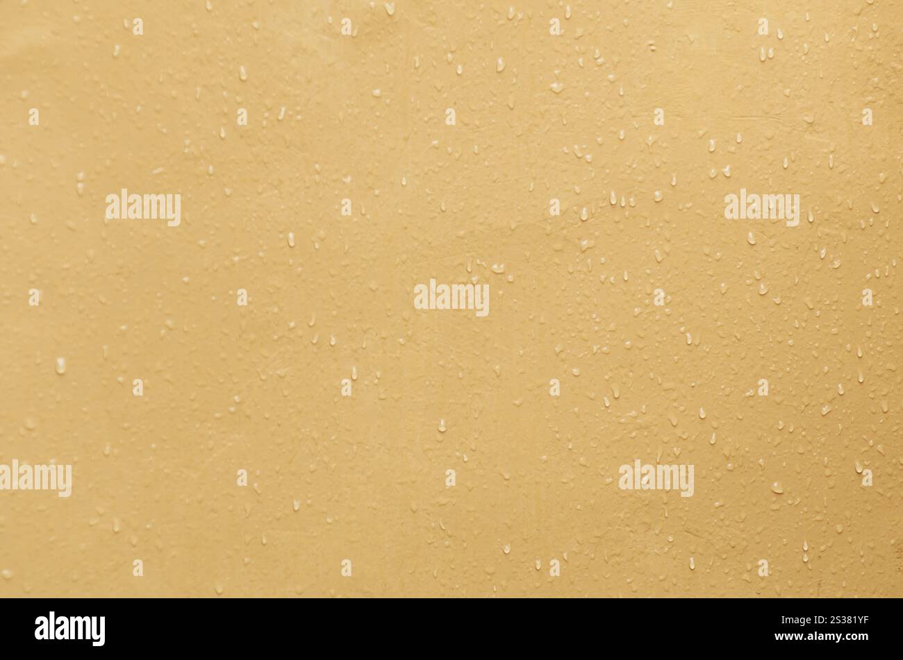 Gelbe strukturierte Wandoberfläche mit Wassertropfenmuster Stockfoto