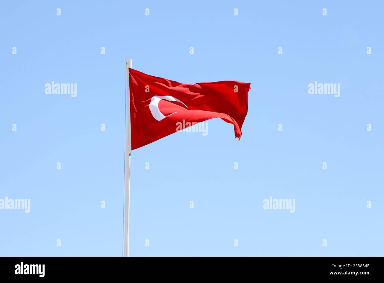 Türkische Flagge auf Fahnenmast winkt im Hintergrund des sauberen blauen Himmels. Weißer Halbmond und Stern auf rotem Hintergrund. Türkische Flagge auf Fahnenmast winkt sauber Stockfoto