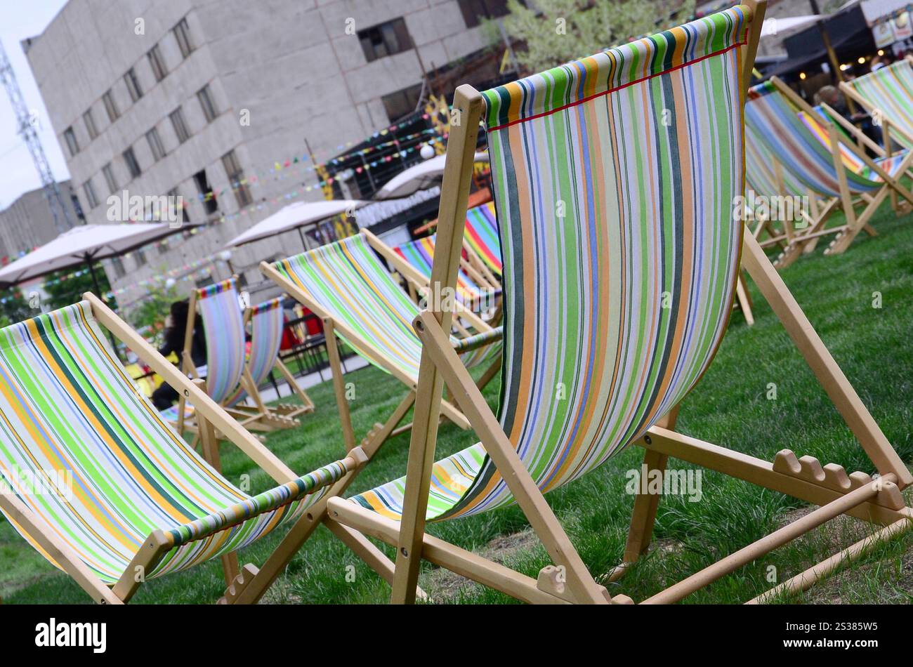 Liegestühle auf einem Rasen. Ruhen Sie sich auf dem Festival aus, im Urlaub. Gartenliegen auf grünem Gras. Gartenbett zum Sonnenbaden und Ausruhen. Sommerstuhl. Chaise Stockfoto