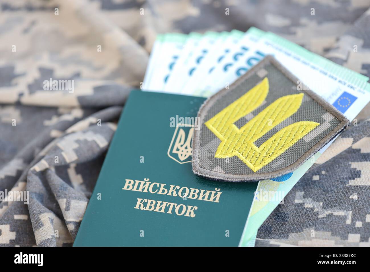 Symbol der ukrainischen Armee und Militärausweis mit einem Haufen Geld auf der Tarnuniform eines ukrainischen Soldaten. Begriff der Zahlung an das Militär Stockfoto Symbol der ukrainischen Armee und Militärausweis mit einem Haufen Geld auf der Tarnuniform eines ukrainischen Soldaten. Begriff der Zahlung an das Militär Stockfoto