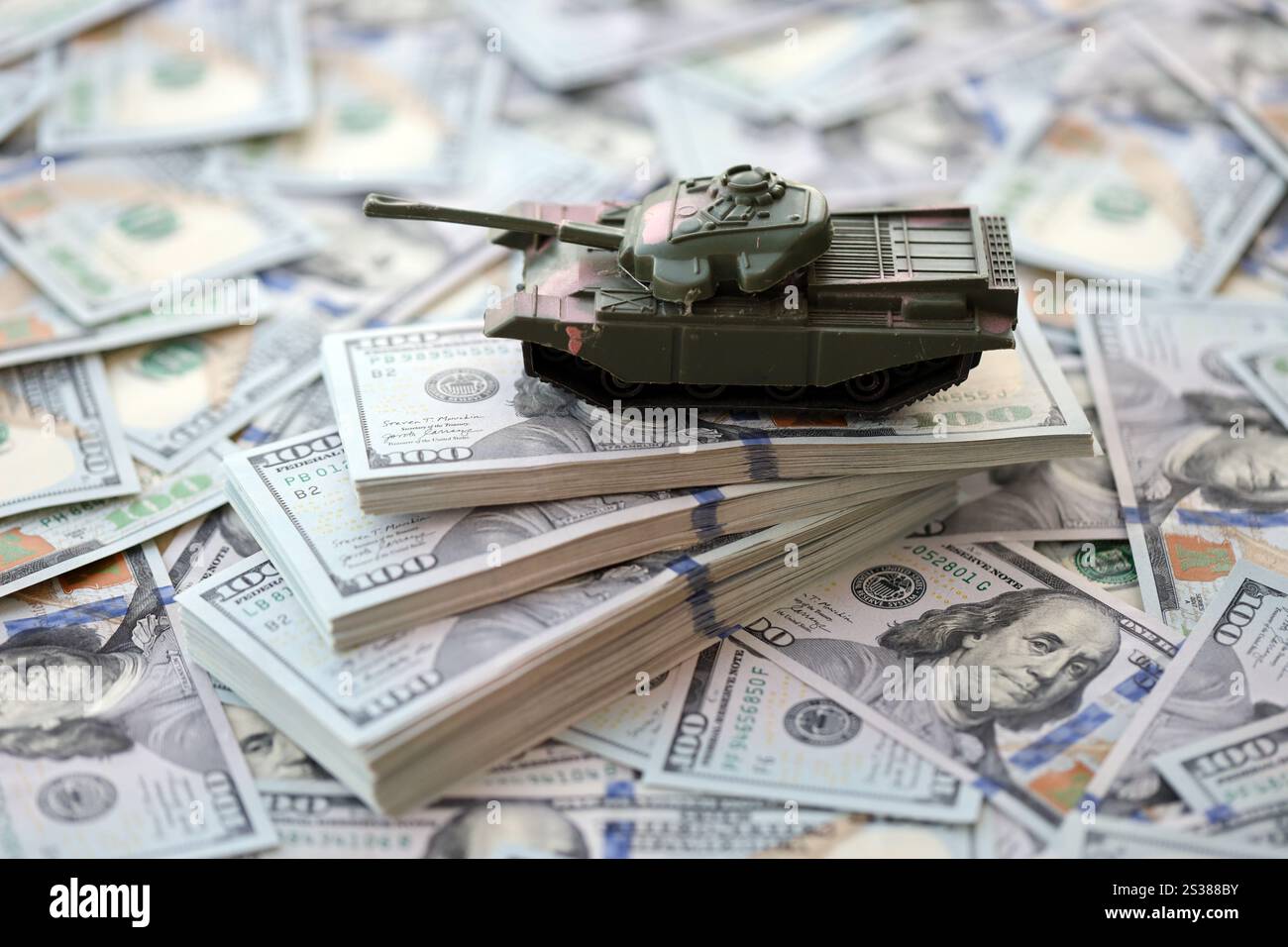 Spielzeugtank auf US-Dollar-Banknoten aus nächster Nähe. Das Konzept der Kriegskosten, der Militärausgaben und der Wirtschaftskrise. Spielzeugtank auf US Hundred Stockfoto
