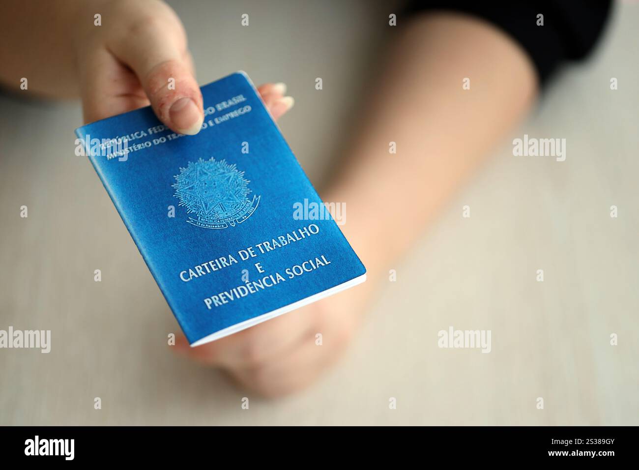 Die Chefin gibt uns im Arbeitsbüro eine brasilianische Arbeitskarte und ein blaues Buch der Sozialversicherung. Die Chefin gibt eine brasilianische Arbeitskarte und Stockfoto