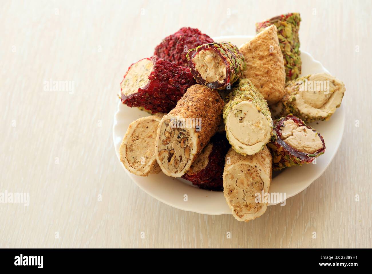 Viele Rollen türkischer Delikatesse mit verschiedenen Aromen und Füllungen auf weißem Teller auf dem Tisch. Teile von türkischen Lokumu-Süßigkeiten. Viele Rollen türkischer Delikatessen Stockfoto