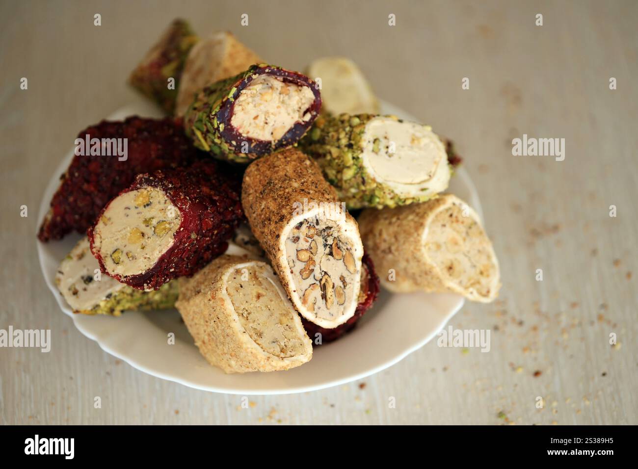 Viele Rollen türkischer Delikatesse mit verschiedenen Aromen und Füllungen auf weißem Teller auf dem Tisch. Teile von türkischen Lokumu-Süßigkeiten. Viele Rollen türkischer Delikatessen Stockfoto