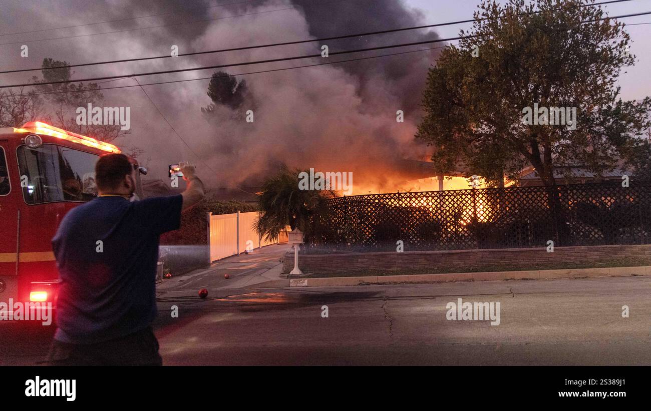 Altadena, Kalifornien, USA 8. Januar 2025. Ein Haus in der Nähe der Ecke Glenrose und Loma Alta Drive bricht in Flammen und schwarzem, schädlichem Rauch in der Wohngegend East Altadena, neben Pasadena, in Los Angeles, Kalifornien: Sein Besitzer macht ein Foto davon. Er wurde durch Funken des Eaton Fire, benannt nach dem Eaton Canyon, einem beliebten Wanderziel in Los Angeles, völlig zerstört. Die Flammen wurden von den Hurrikanwinden von Santa Ana geschürt. Die meisten Häuser wurden dezimiert und Dutzende brennen immer noch in Flammen und schwelen. (Bild: © Amy Kat Stockfoto