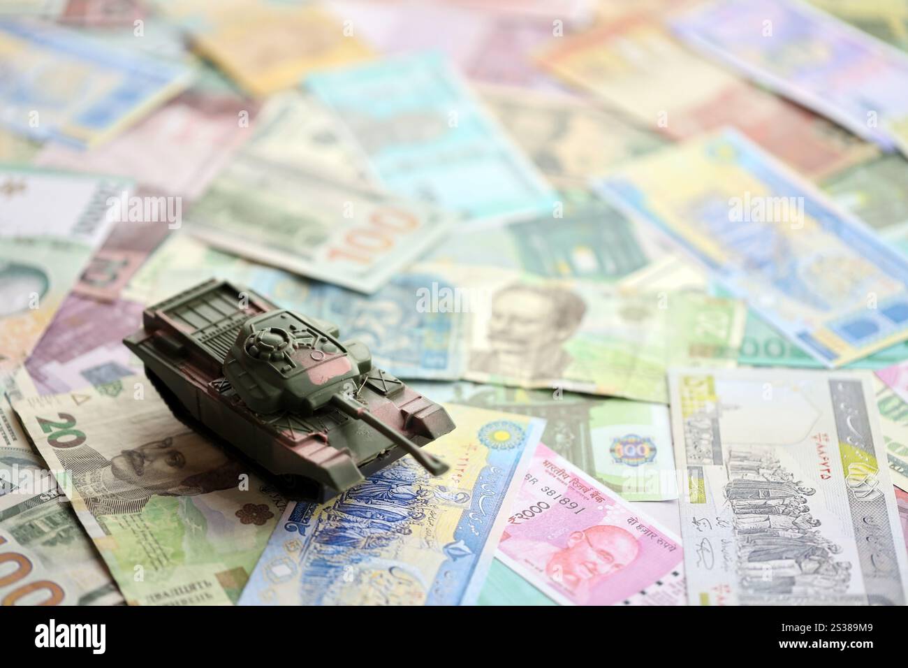 Kleiner grüner Tank auf vielen Banknoten verschiedener Währungen. Hintergrund der Kriegsfinanzierung oder Geld für die Verteidigung aus der Nähe. Kleiner grüner Tank auf vielen Stockfoto