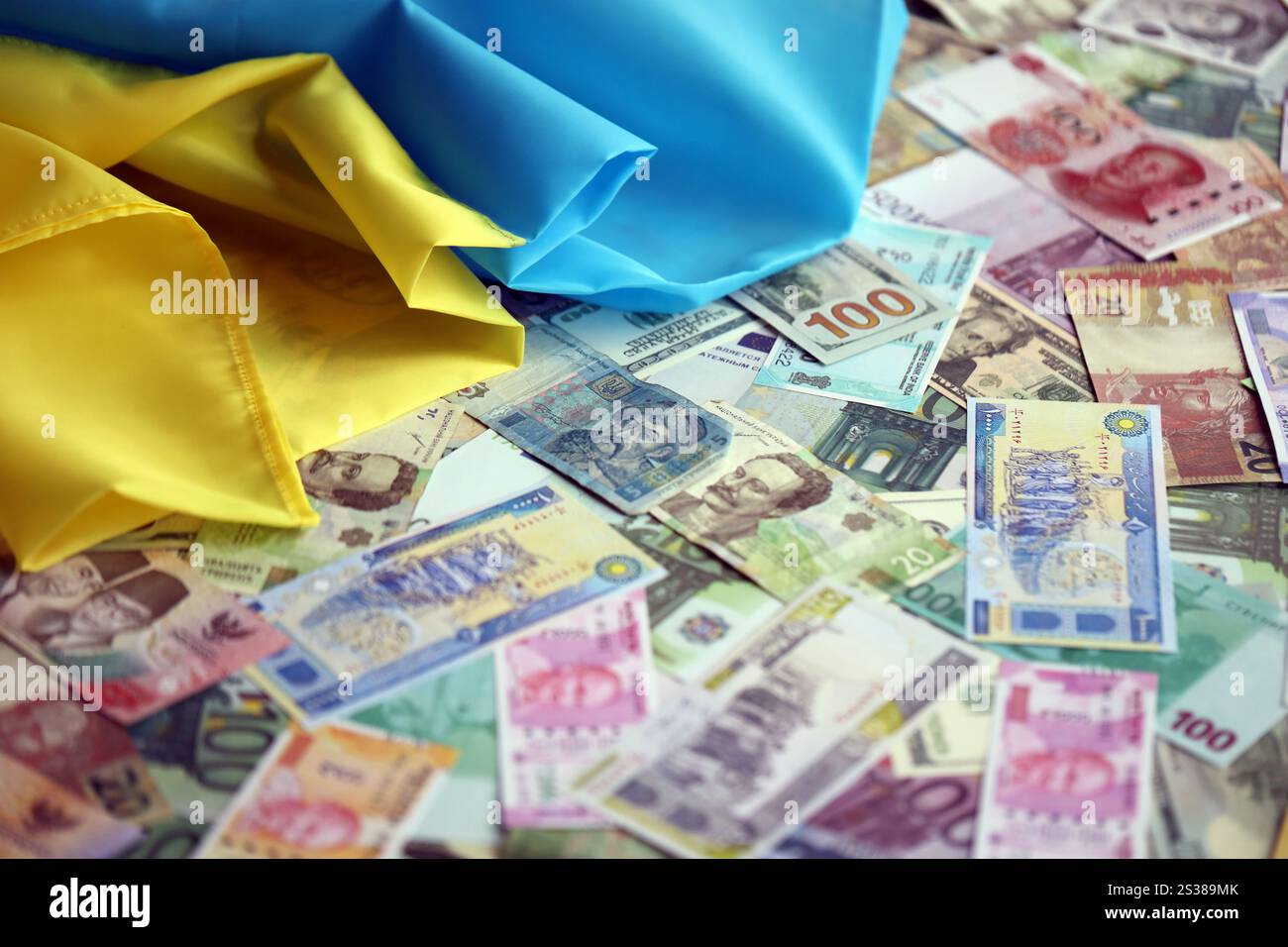 Ukrainische Flagge auf vielen Banknoten verschiedener Währungen. Hintergrund der Kriegsfinanzierung und des Preises für militärische Unterstützung in der Ukraine. Ukrainische Flagge auf vielen Stockfoto