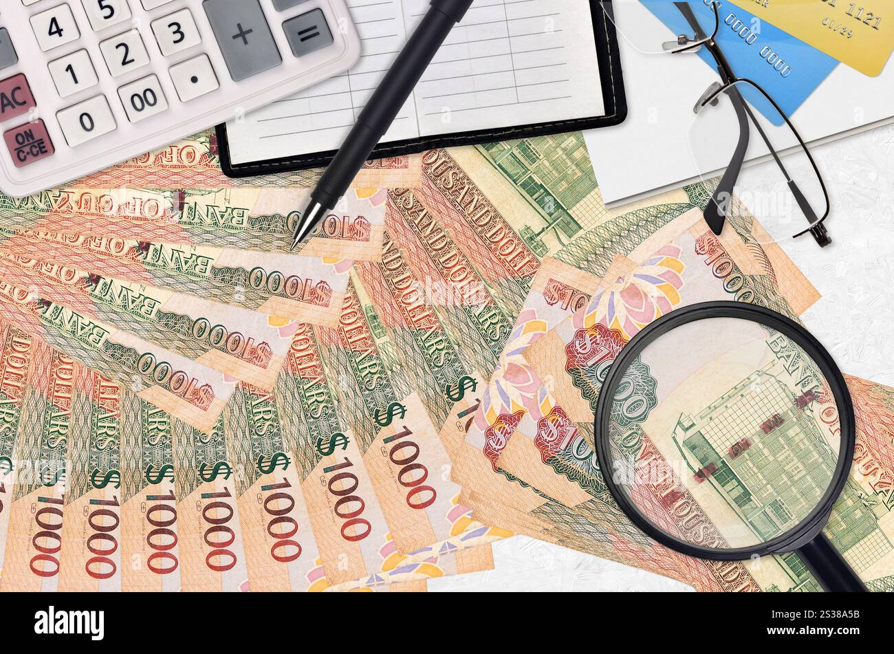 1000 Guyanesische Dollar Rechnungen und Rechner mit Brille und Stift. Tax Payment Saison Konzept oder Investment-Lösungen. Suche nach einem Job mit hohem Gehalt Stockfoto