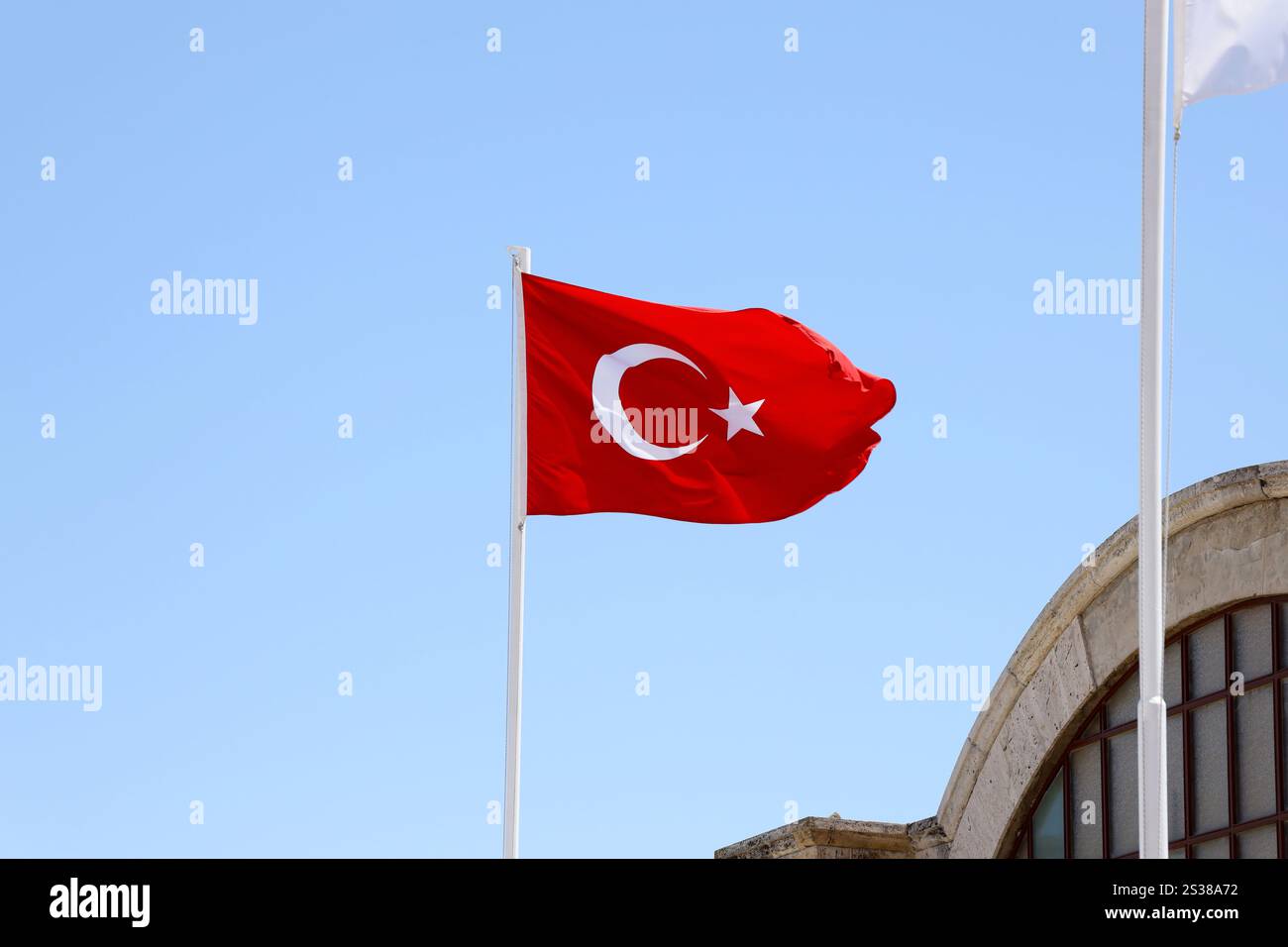 Türkische Flagge auf Fahnenmast winkt im Hintergrund des sauberen blauen Himmels. Weißer Halbmond und Stern auf rotem Hintergrund. Türkische Flagge auf Fahnenmast winkt sauber Stockfoto