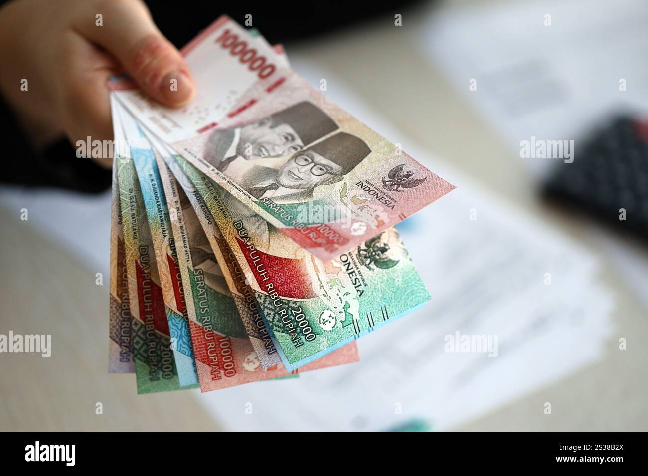 Weibliche Buchhalterin Hand gibt einen Haufen von vielen indonesischen Rupiah Geldscheine der neuen Serien Nahaufnahme. Weibliche Buchhalterin Hand gibt einen Haufen von vielen indonesiern Stockfoto