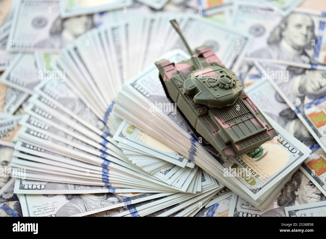 Spielzeugtank auf US-Dollar-Banknoten aus nächster Nähe. Das Konzept der Kriegskosten, der Militärausgaben und der Wirtschaftskrise. Spielzeugtank auf US Hundred Stockfoto