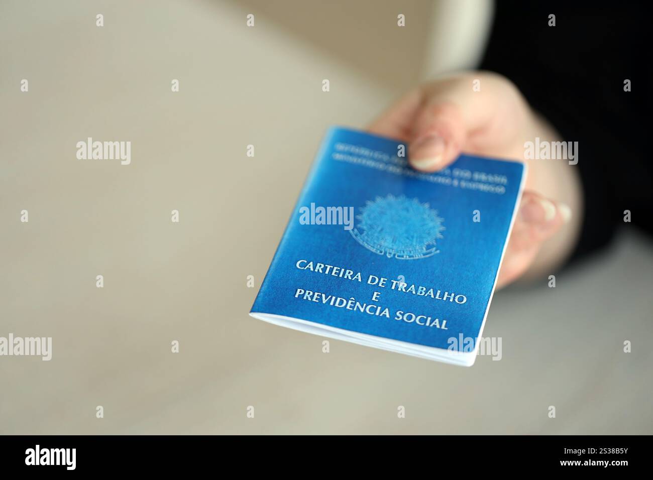 Die Chefin gibt uns im Arbeitsbüro eine brasilianische Arbeitskarte und ein blaues Buch der Sozialversicherung. Die Chefin gibt eine brasilianische Arbeitskarte und Stockfoto