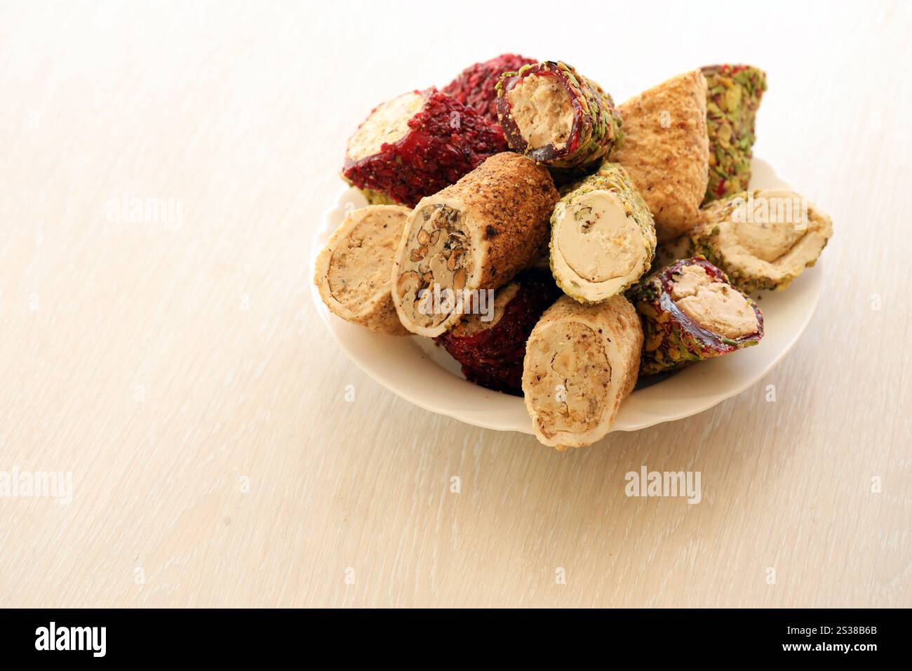 Viele Rollen türkischer Delikatesse mit verschiedenen Aromen und Füllungen auf weißem Teller auf dem Tisch. Teile von türkischen Lokumu-Süßigkeiten. Viele Rollen türkischer Delikatessen Stockfoto