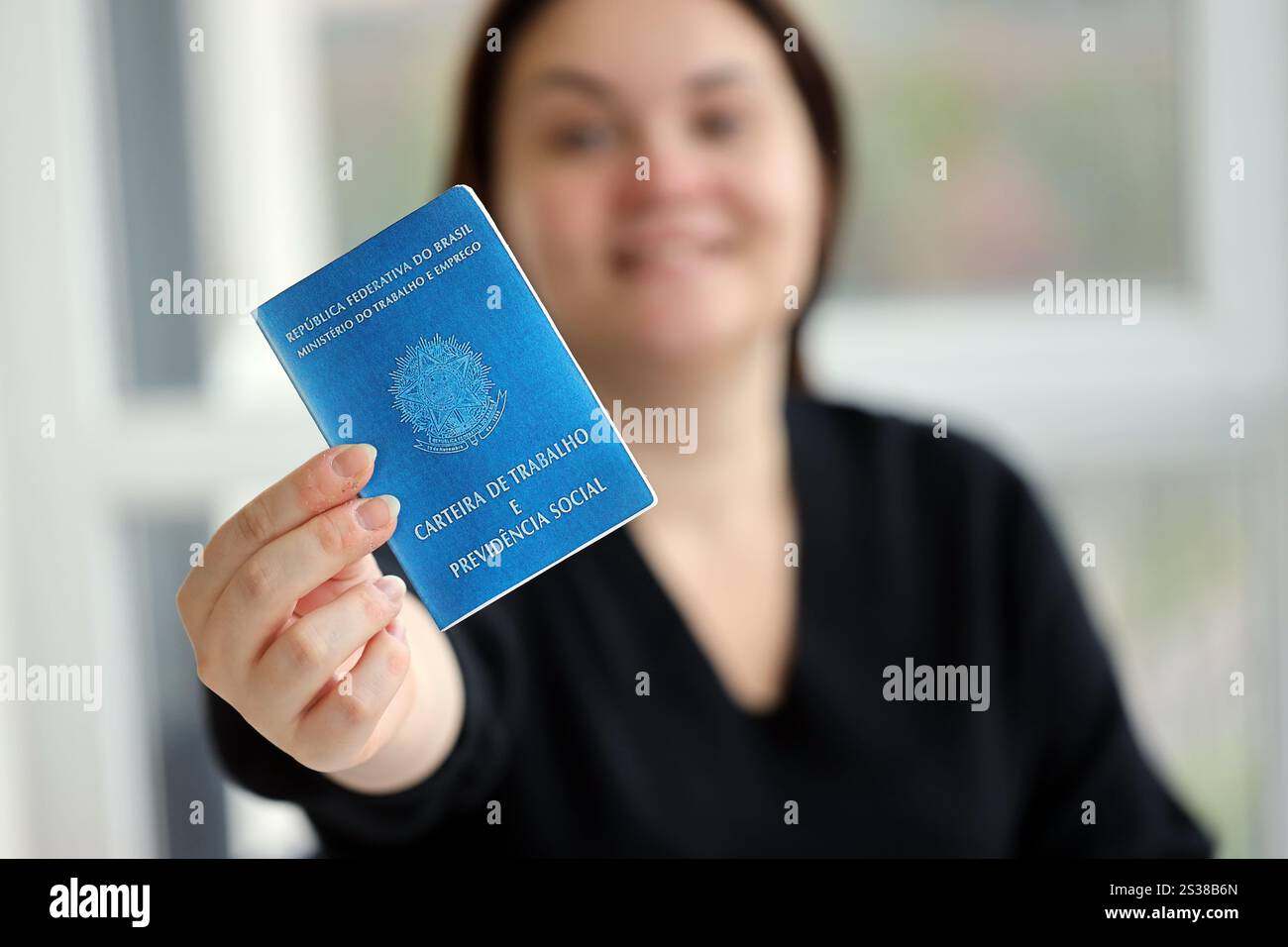 Die Chefin gibt uns im Arbeitsbüro eine brasilianische Arbeitskarte und ein blaues Buch der Sozialversicherung. Die Chefin gibt eine brasilianische Arbeitskarte und Stockfoto