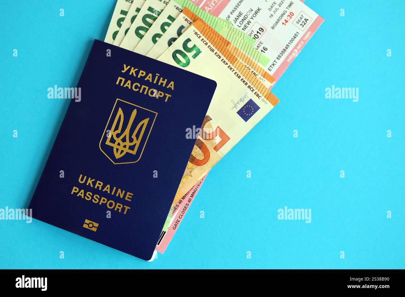 Ukrainischer biometrischer Pass und europäische Euro-Geldscheine mit Airlines avia Tickets auf blauem Hintergrund Nahaufnahme. Ukrainischer biometrischer Pass Stockfoto