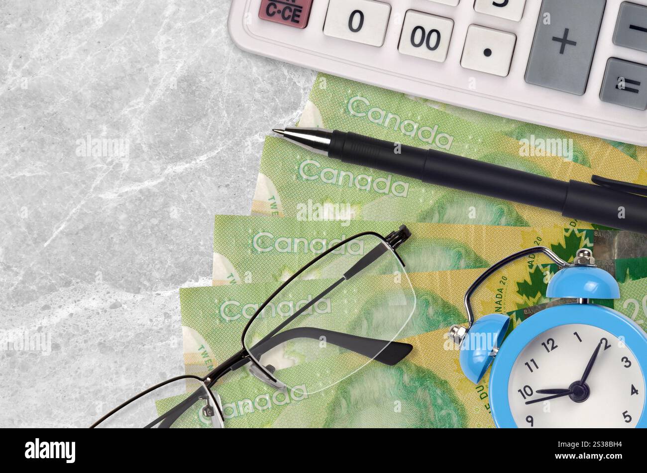 20 kanadische Dollarscheine und Taschenrechner mit Brille und Stift. Geschäftsdarlehen oder Steuerzahlung Saisonkonzept. Finanzplanung und Zeit für die Zahlung von Steuern. Stockfoto