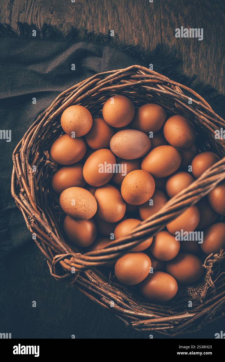 Braune Bio-Eier in einem Korb auf Holztisch Stockfoto
