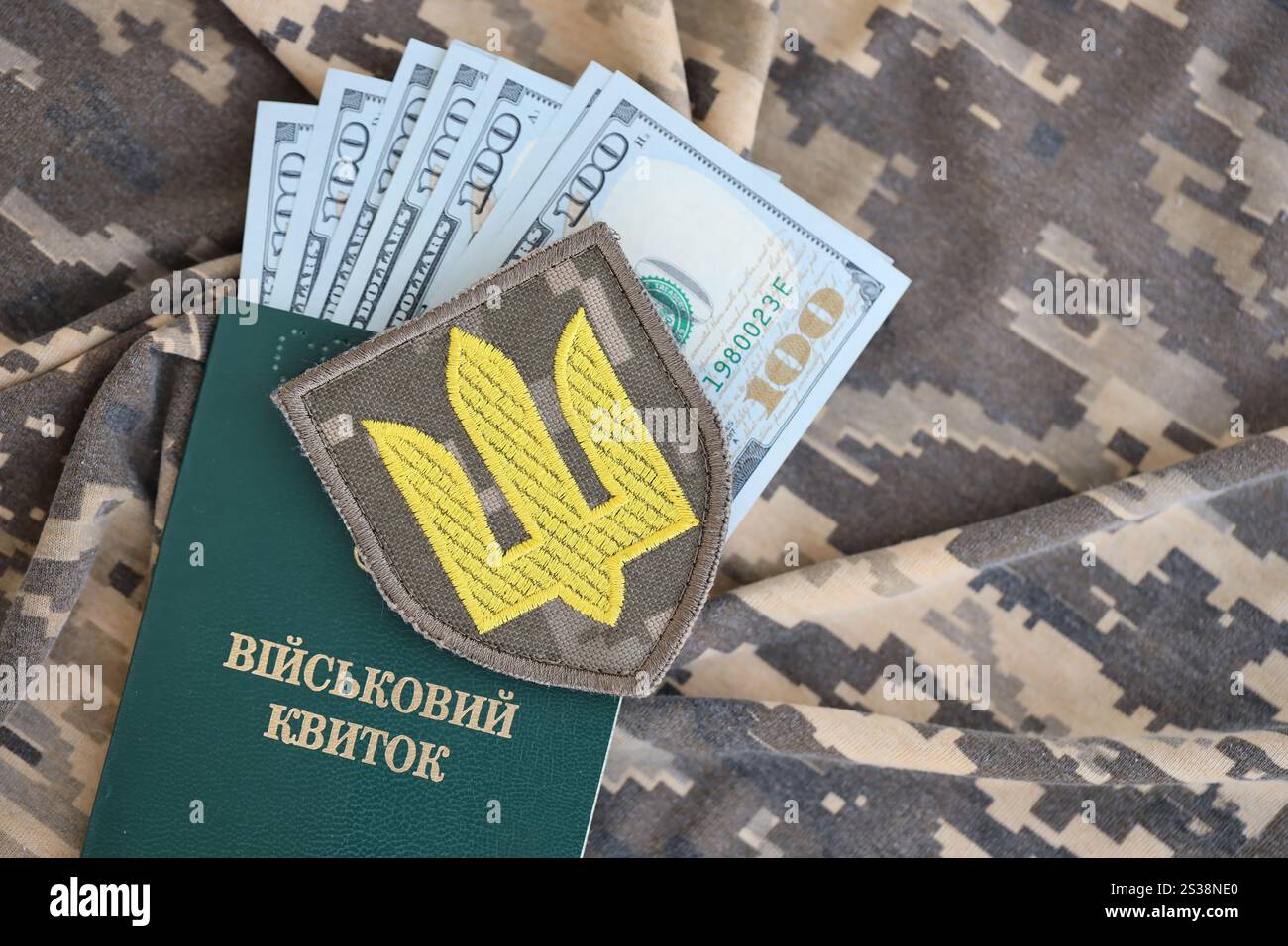 Symbol der ukrainischen Armee und Militärausweis mit einem Haufen Geld auf der Tarnuniform eines ukrainischen Soldaten. Begriff der Zahlung an das Militär Stockfoto Symbol der ukrainischen Armee und Militärausweis mit einem Haufen Geld auf der Tarnuniform eines ukrainischen Soldaten. Begriff der Zahlung an das Militär Stockfoto