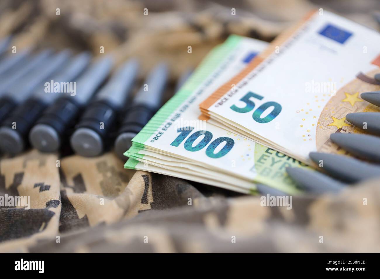 Bündel Euroscheine und ein Maschinengewehrgürtel auf der Tarnuniform eines ukrainischen Soldaten. Konzept der Kriegsfinanzierung, Bestechung oder Spende. Hilfe zu Stockfoto
