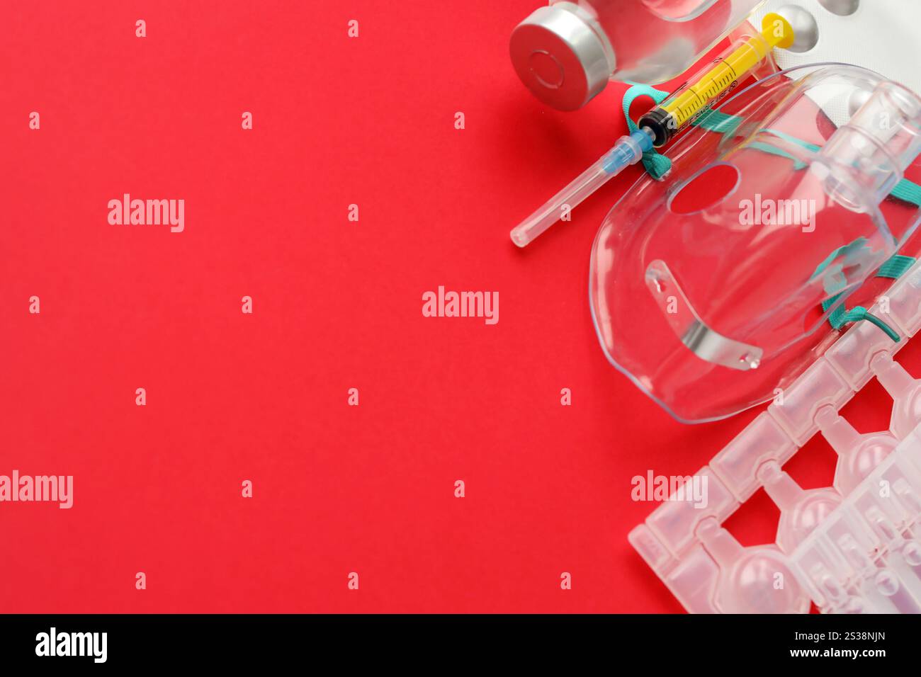 Coronavirus-Behandlungskonzept. Eine medizinische Gesichtsmaske Vernebler für die Behandlung der Atemwege und Packs von Ampullen flach auf rotem Hintergrund gelegt. Stockfoto