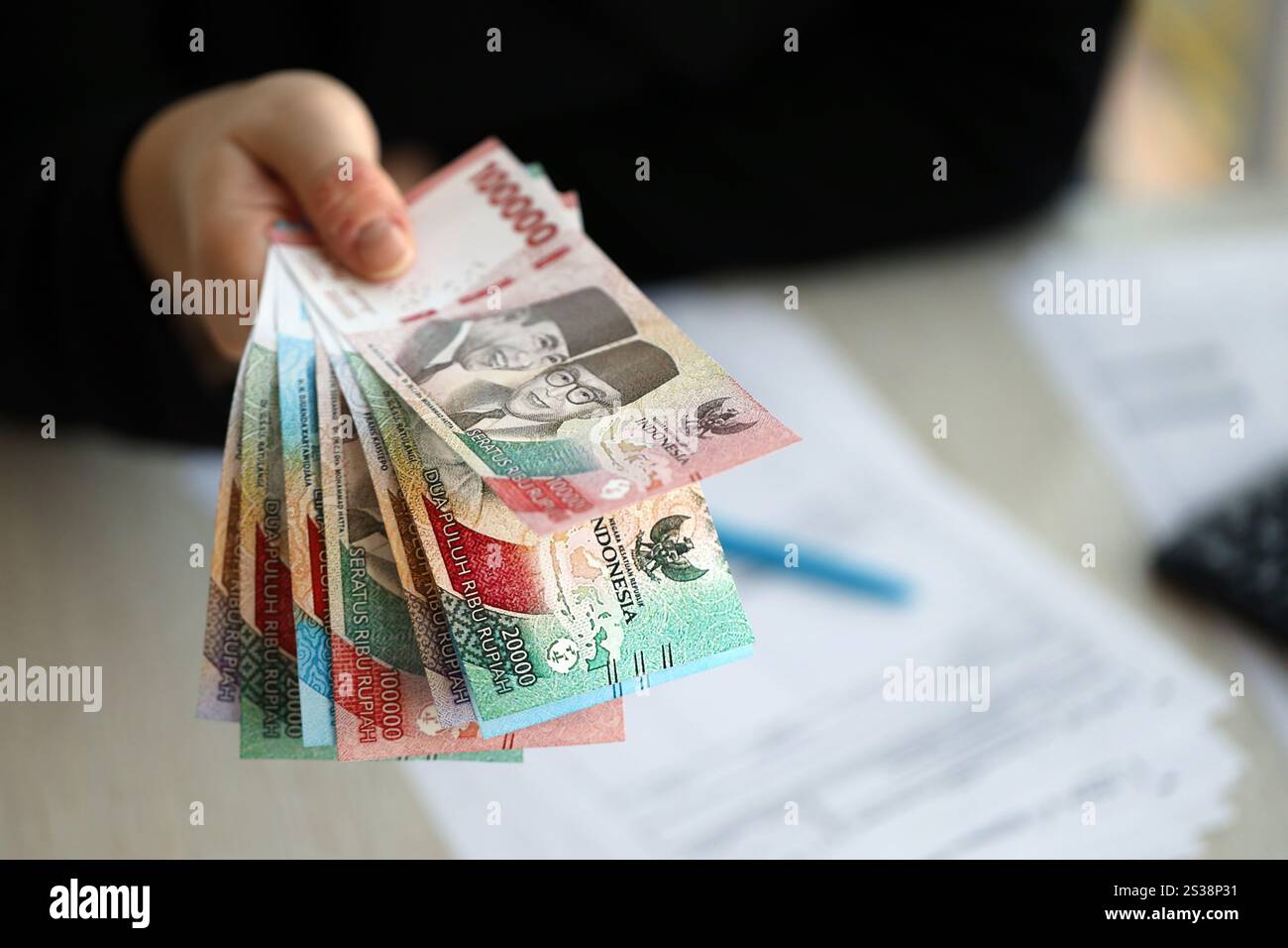 Weibliche Buchhalterin Hand gibt einen Haufen von vielen indonesischen Rupiah Geldscheine der neuen Serien Nahaufnahme. Weibliche Buchhalterin Hand gibt einen Haufen von vielen indonesiern Stockfoto