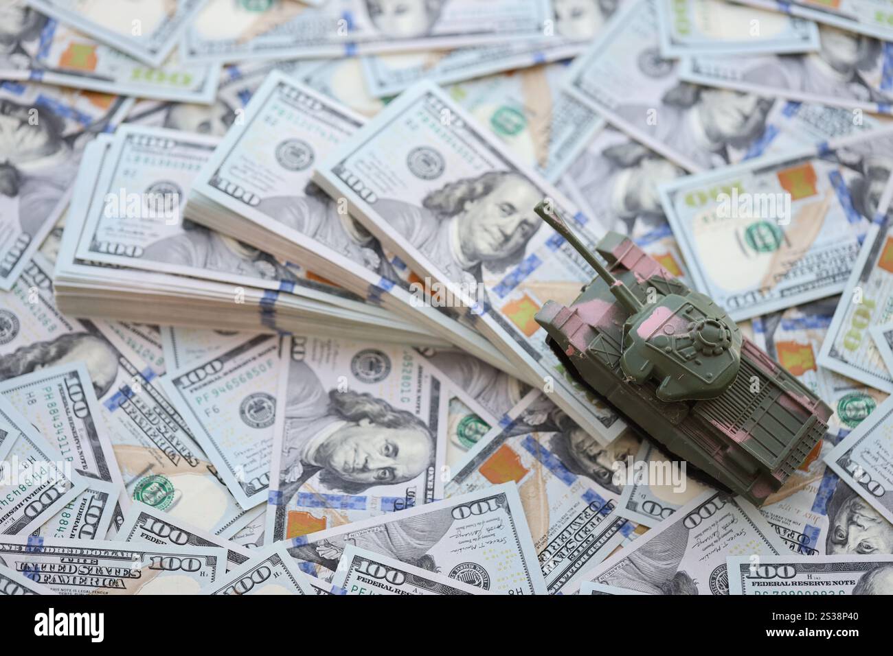 Spielzeugtank auf US-Dollar-Banknoten aus nächster Nähe. Das Konzept der Kriegskosten, der Militärausgaben und der Wirtschaftskrise. Spielzeugtank auf US Hundred Stockfoto