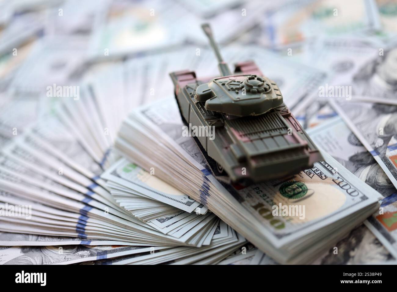 Spielzeugtank auf US-Dollar-Banknoten aus nächster Nähe. Das Konzept der Kriegskosten, der Militärausgaben und der Wirtschaftskrise. Spielzeugtank auf US Hundred Stockfoto