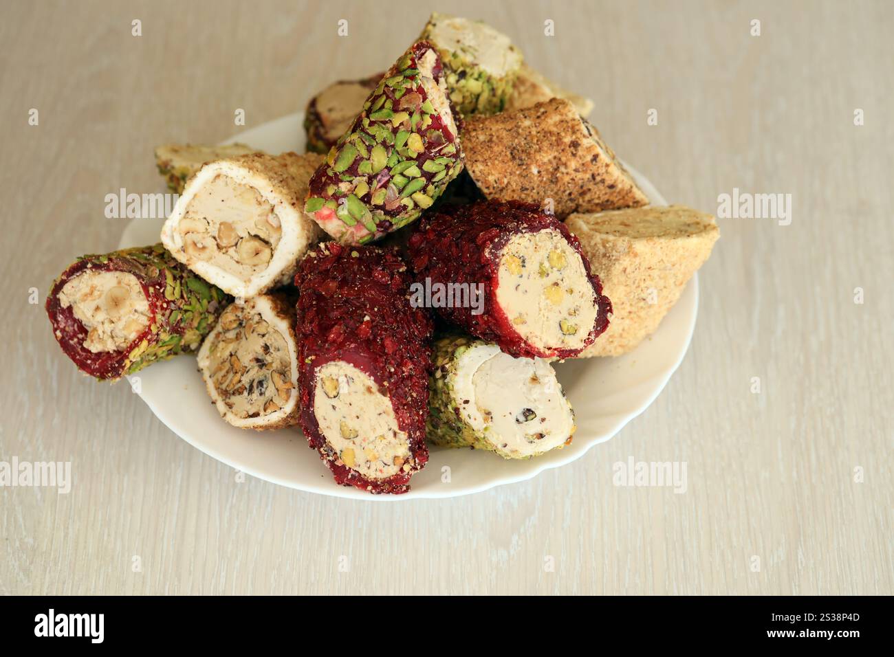 Viele Rollen türkischer Delikatesse mit verschiedenen Aromen und Füllungen auf weißem Teller auf dem Tisch. Teile von türkischen Lokumu-Süßigkeiten. Viele Rollen türkischer Delikatessen Stockfoto