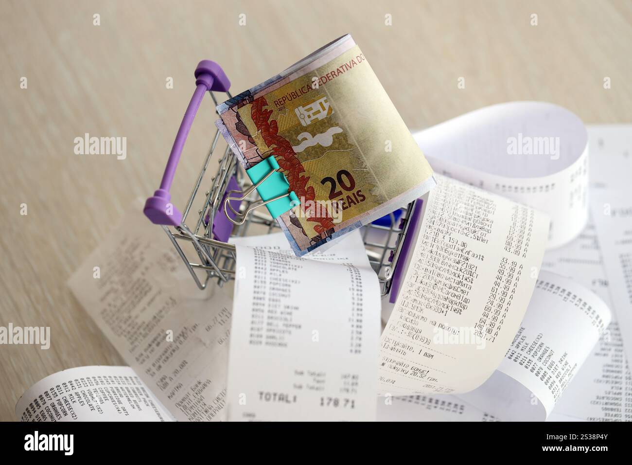 Brasilianische Reais-Geldscheine im Einkaufswagen, umgeben von vielen Papierquittungen aus der Nähe. Brasilianische Reais-Geldscheine beim Einkaufen Stockfoto