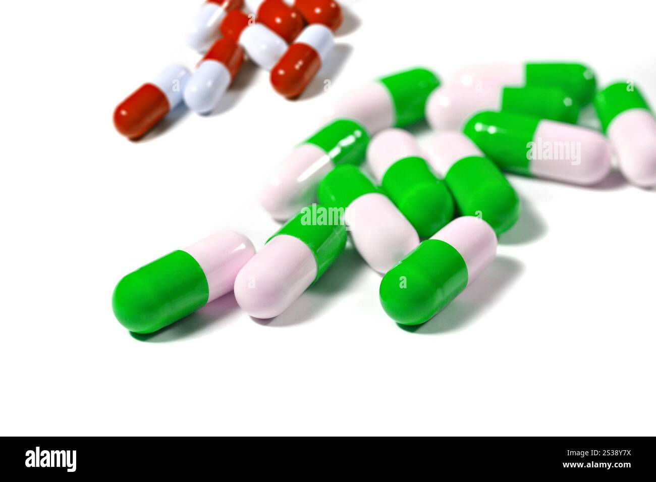 Nahaufnahme von verstreuten grünen, weißen und roten Kapselpillen, isoliert auf einer weißen Oberfläche. Bunte Kapselpillen auf weißem Hintergrund Stockfoto